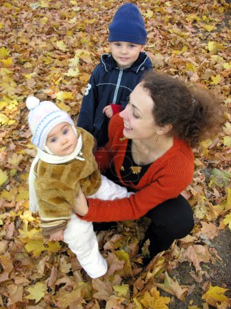 Mother with children on autumn leaves