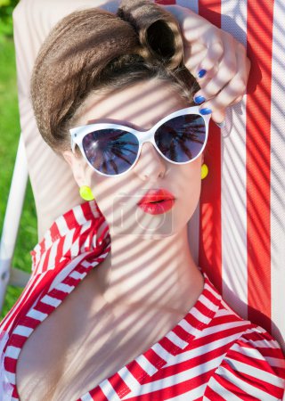 Woman wearing sunglasses lying down on a deck chair