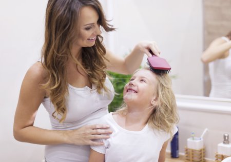 Mother brushes daughter's hair