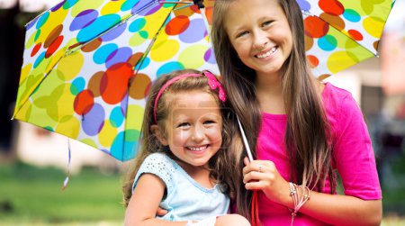 Young sisters posing with colorful umbrella
