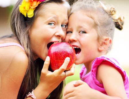 Joyful cute kids sharing an apple