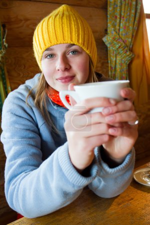 Apres ski, winter holiday - young snowboarder girl resting in mountain hut