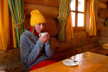 Apres ski, winter holiday - young snowboarder girl resting in mountain hut