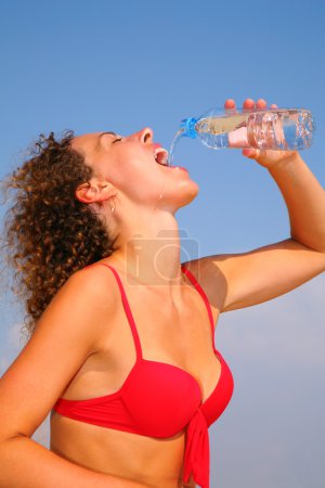 Girl in red bikini drinking water