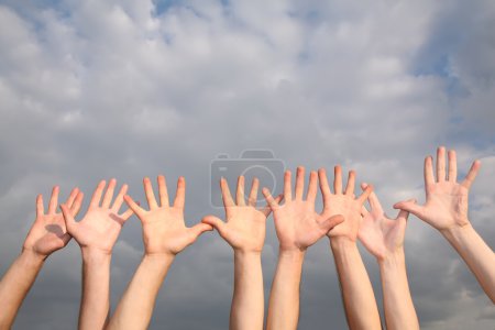 Raised hands on cloudy sky background 2