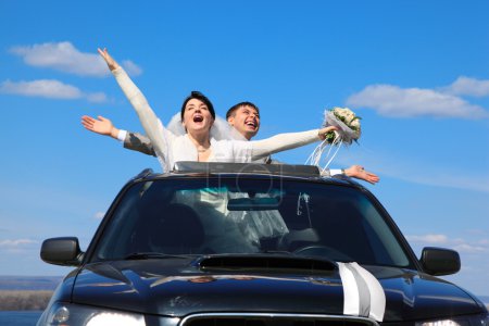 Fiance and bride are glad standing in car