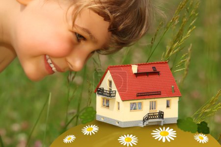 Child looks on model of house outdoor