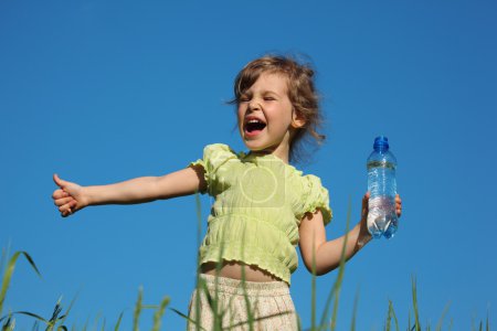 Screaming girl in grass with plastic bottle with water