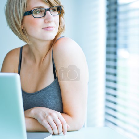 Portrait of a young woman pensively looking out of the window