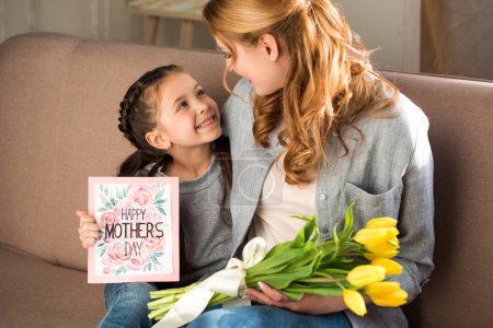 happy mother and daughter holding yellow tulips and happy mothers day greeting card