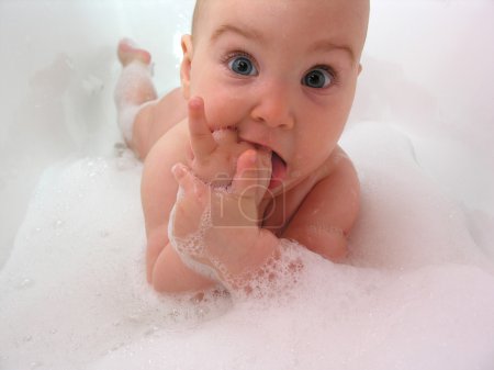 Baby in bath. hand in mouth