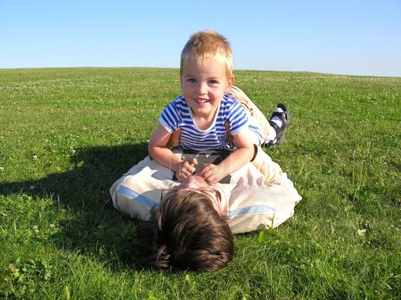 Son lie on father on green grass 2