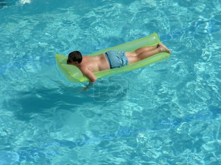 Boy on mattress in pool