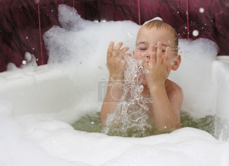 Boy in bath with splash of water in hands