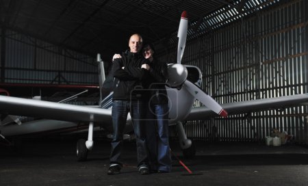 Happy young couple posing in front of private airplane
