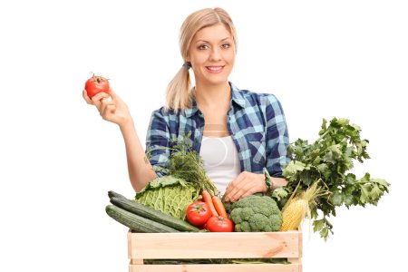 Woman standing behind a crate with vegetables 
