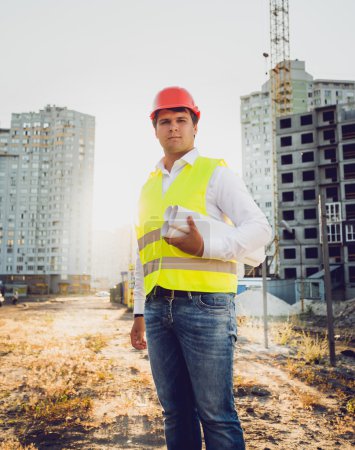 Toned photo of engineer posing against building site at sunset
