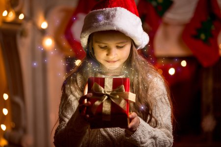 Cute girl looking inside of glowing Christmas present box