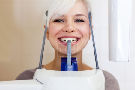 smiling blonde woman is doing a dental scan