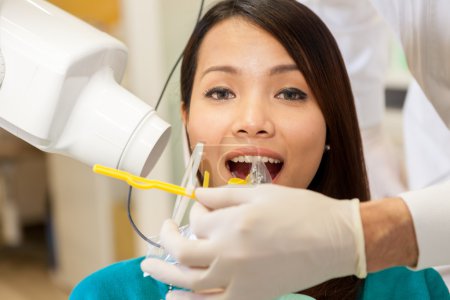 asian woman si doing dental scan on specific teeth