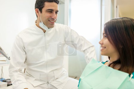 asian male dentist is speaking with his patient 