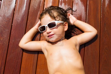 Toddler baby kid in summer sun tanning on wood
