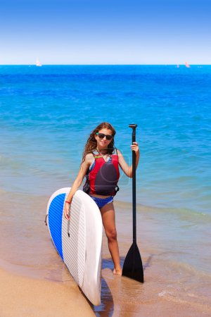 Kid paddle surf surfer girl with row in the beach