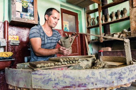 Potter adding handle to fresh clay manufactured pottery