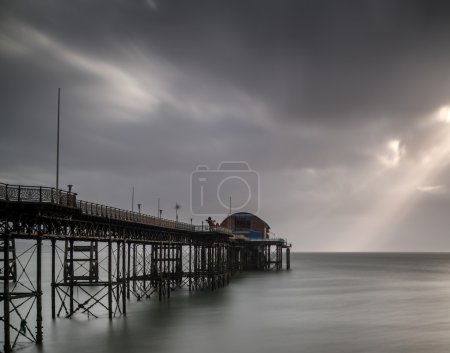 Long exposure landscape of Victorian pier  witn moody sky