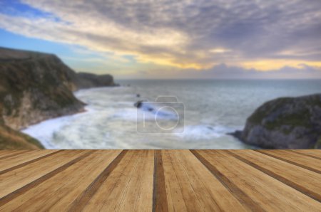 Vibrant sunrise over ocean and sheltered cove with wooden planks