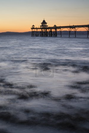 Long exposure landscape image of pier at sunset in Summer