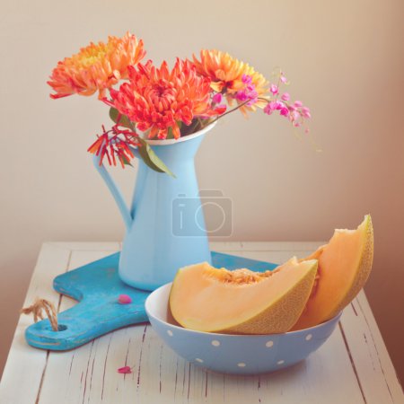 Melon and flowers on vintage table. Focus on melon. Retro filter effect