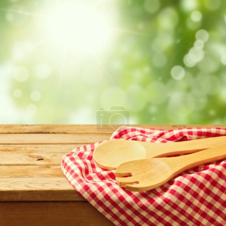 Wooden spoon on tablecloth over garden bokeh background