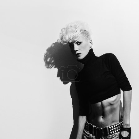 Blond model on wall background with shadow. Stylish haircut. pun