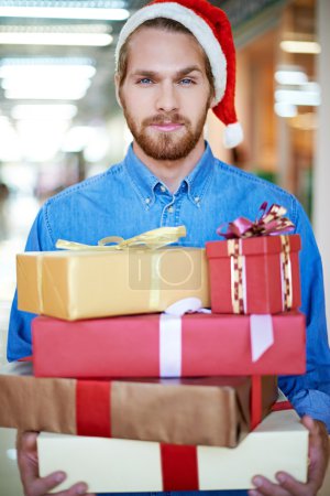 Man in Santa cap holding gift boxes