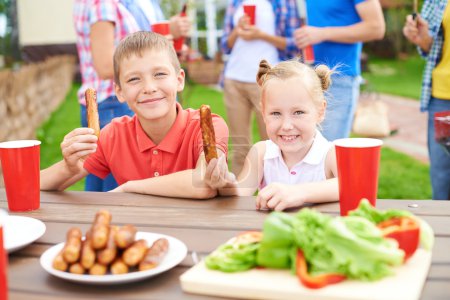 Children eating grilled sausages