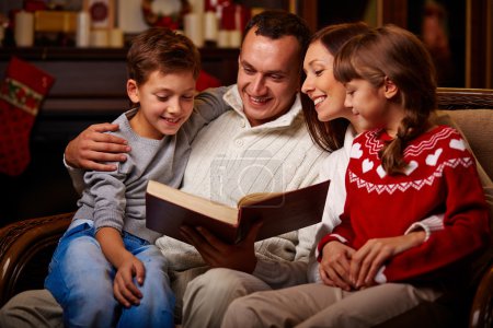 Family reading book on Christmas evening