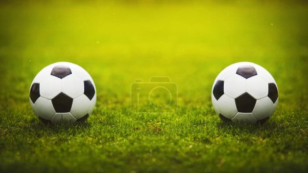 Two classic soccer balls, one in front another, placed on the green grass stadium turf. Traditional football playing ball on natural lawn with copy space for match announcements. Tournament rivalry