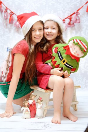 Two smiling sisters wearing santa hats