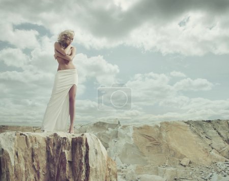 Blond lady standing on the edge of the mountain