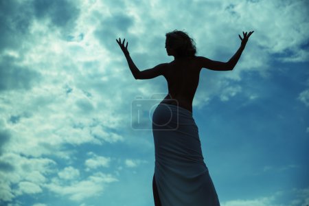 Half-naked woman posing over the blue sky