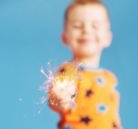 Blurred portrait of boy holding a sparkler