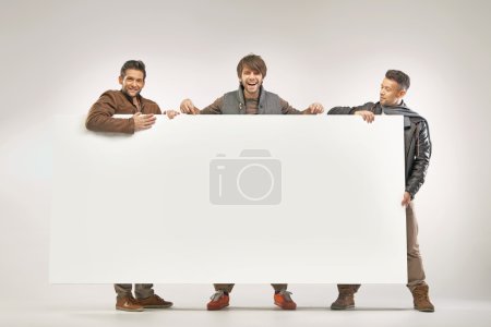 Three cheerful guys holding the board