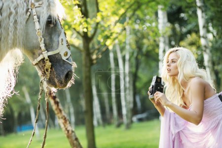 Beautiful woman taking pictures of the horse