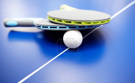Two table tennis or ping pong rackets and balls on a blue table