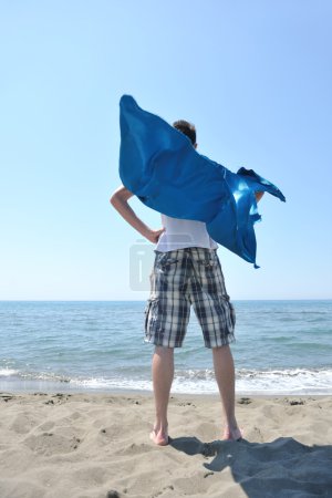 Funny superhero standing on beach