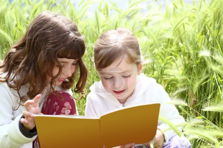 Tow little sister girls reading book spikes garden