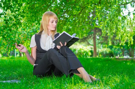 Business woman with notebook on grass