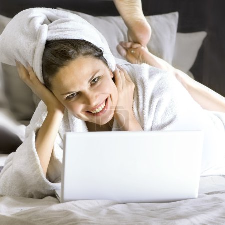 Happy woman on the bed with laptop