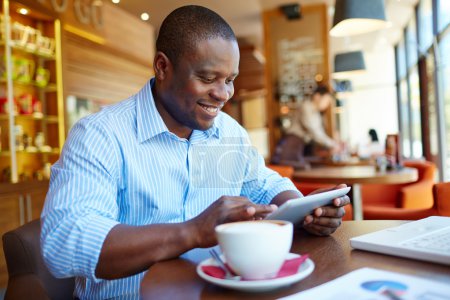 Man using digital tablet in cafe